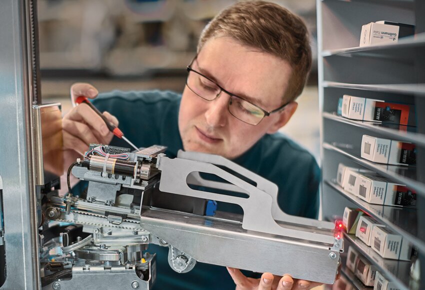 Empleado ajustando la pinza de un robot farmacéutico